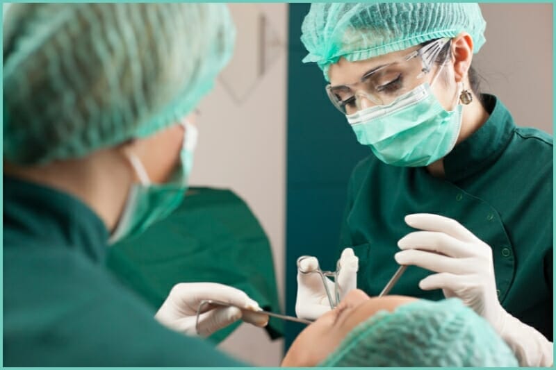 dentists in dark forrest green performing a wisdom teeth removal