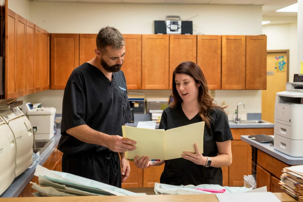 Dr. Yanich and a woman looking at paperwork in a manila folder