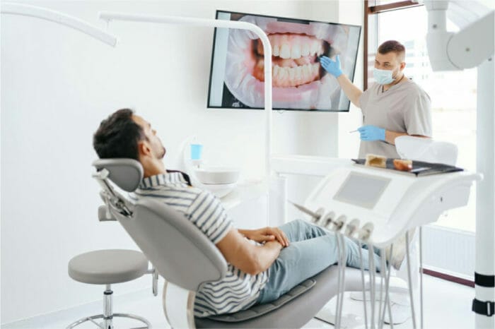 Dentist consulting with a patient in a modern dental office while displaying detailed images of teeth and gums on a screen.