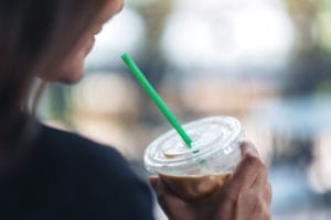 woman holding a drink with a green straw
