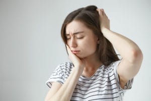 woman in a striped shirt holding her chin and head