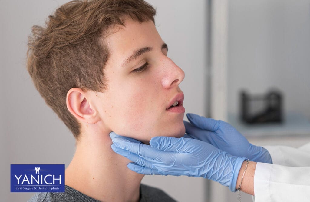 "Dentist wearing blue gloves examining a male patient's jaw during a dental check-up.