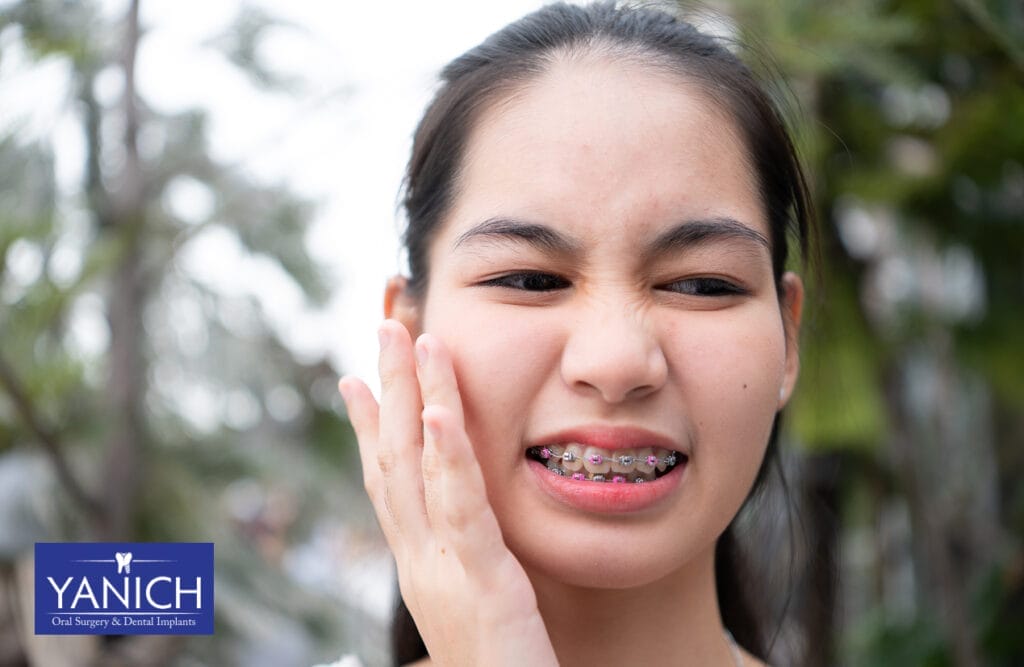 Woman touching her jaw with a pained expression, indicating discomfort or pain.