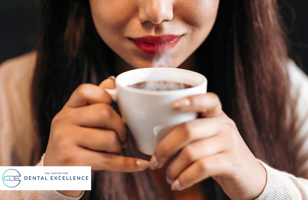 Woman enjoying a cup of hot coffee, symbolizing lifestyle choices linked to dental staining and oral care awareness.