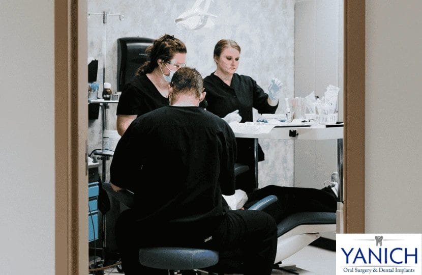 Dental team conducting a surgical procedure in a treatment room, showcasing professional collaboration and patient care.
