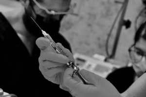 Black and white photo of syringe with anesthesia held before wisdom teeth procedure