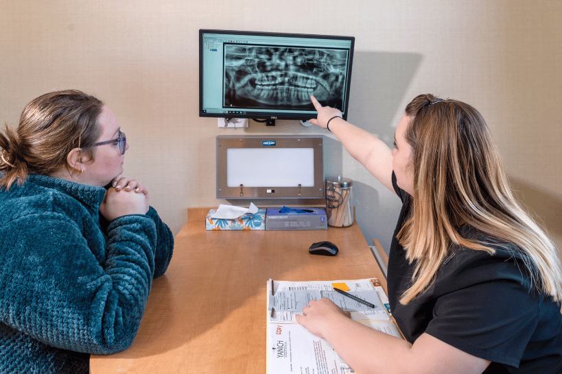 Yanich Oral Surgery professional explaining wisdom tooth X-ray to patient on monitor